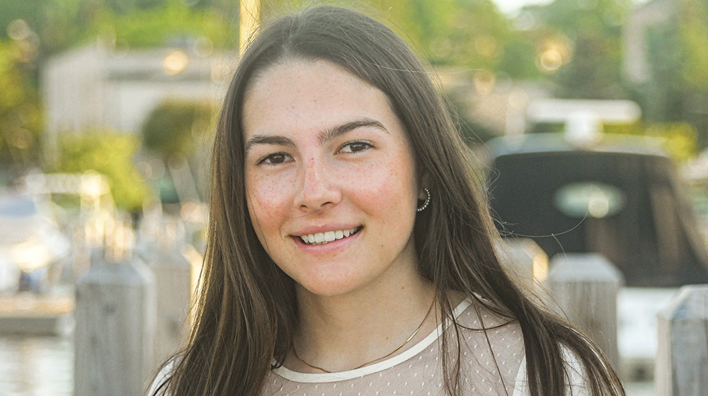 Portrait of Loyola University Chicago student smiling outdoors near waterfront docks at sunset